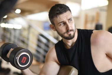 A determined man lifting a dumbbell indoors, showcasing strength and fitness.